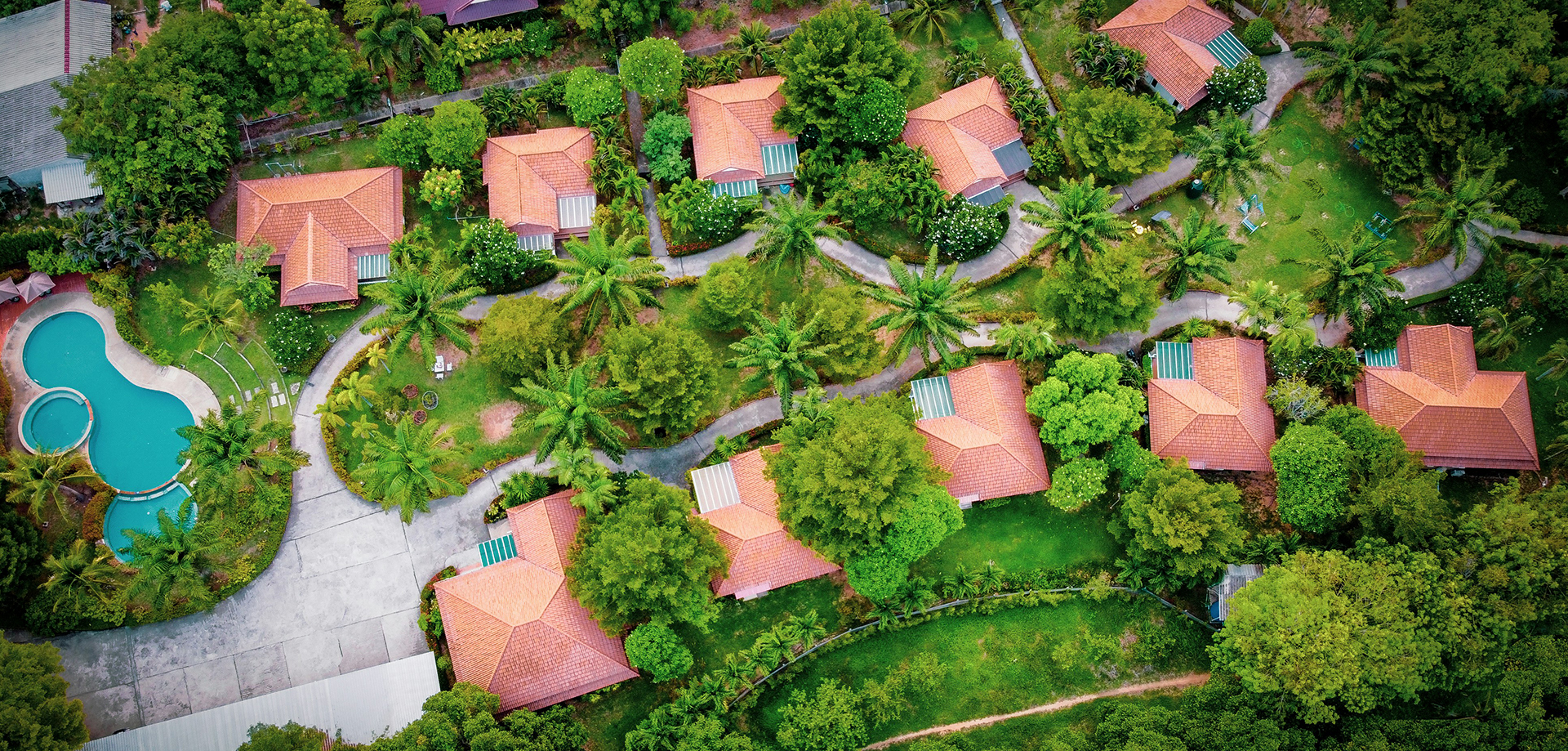 Aerial view of a tropical resort with villas and pools.