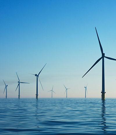 Renewable energy represented by silhouetted wind turbines silhouetted against a dramatic sunset.